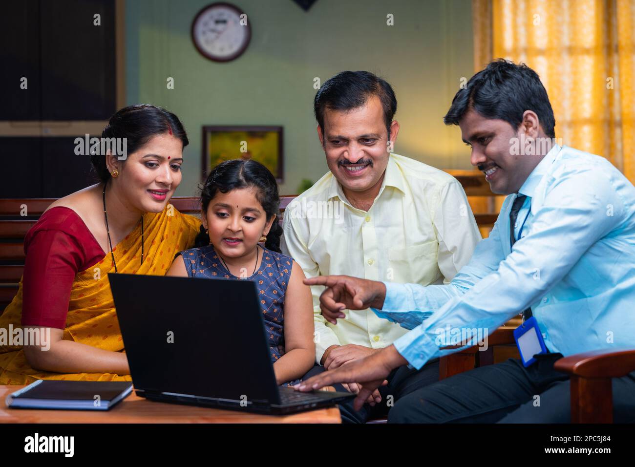 Bank officer explaining about child insurance or loan policy to couple at home - concept of financial services, togetherness, and future investment Stock Photo