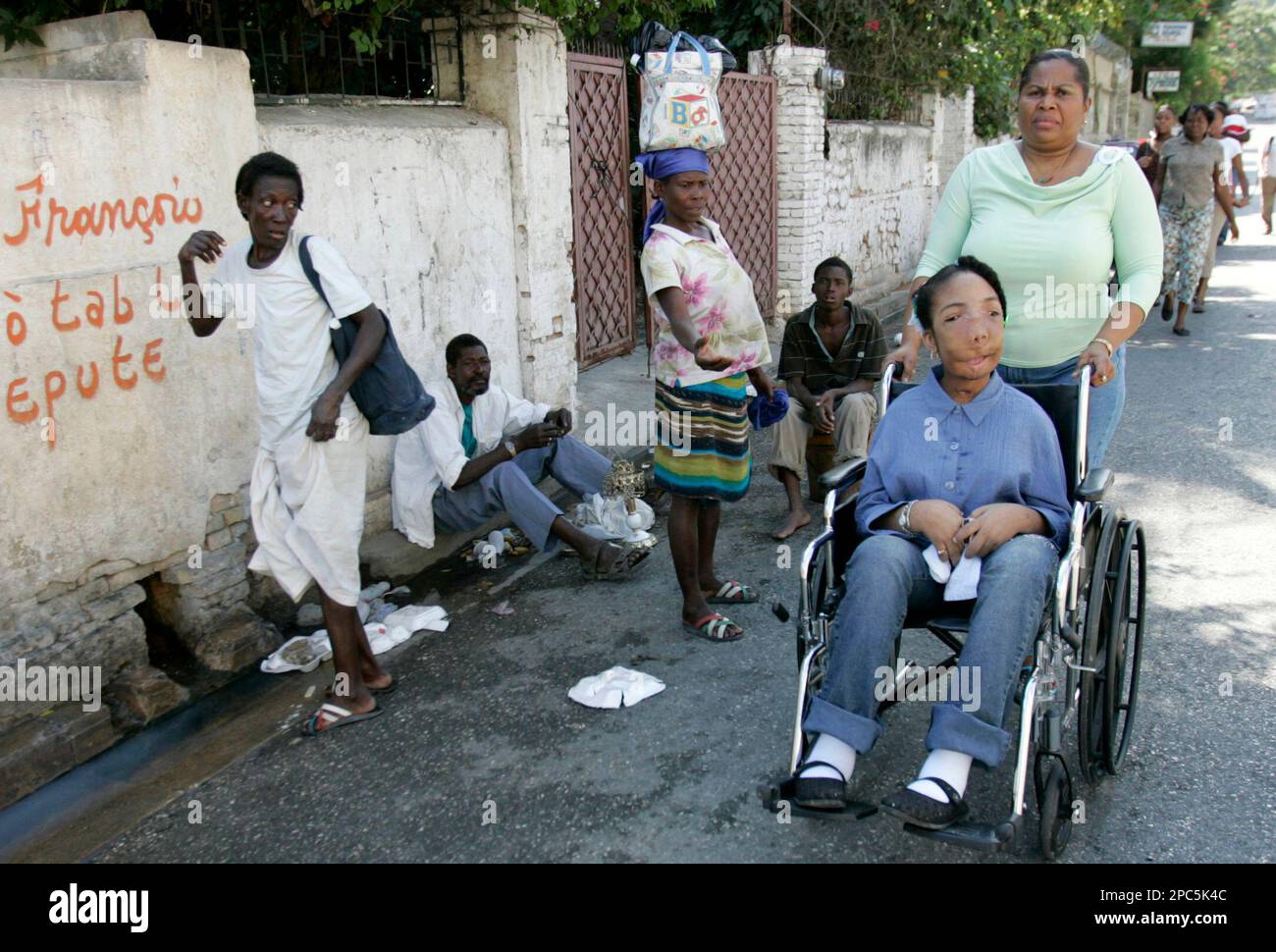Marlie Casseus is pushed in a wheelchair by her mother, Maleine Antoine, as  a woman begs on their way to church in Port-au-Prince, Haiti, Sunday, Dec.  24, 2006. A rare form of