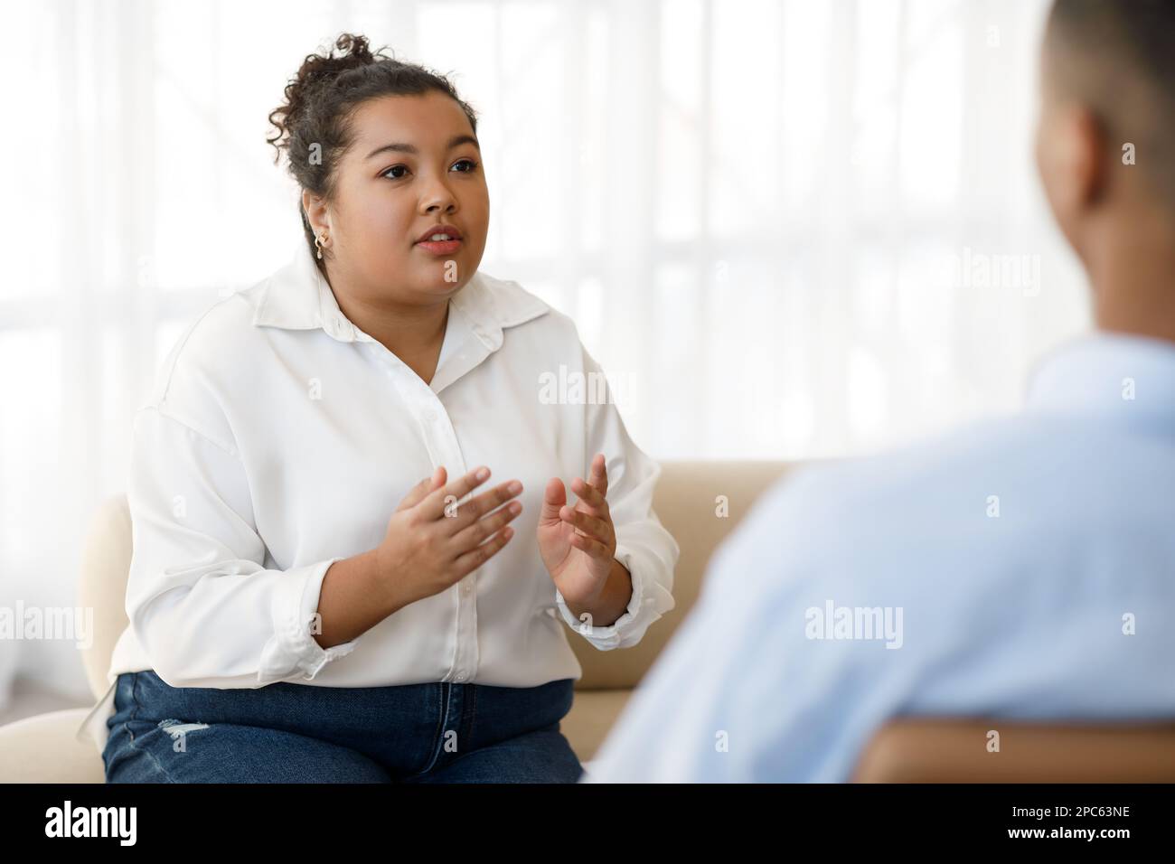 Pretty young mixed race woman plus size visiting psychologist Stock Photo