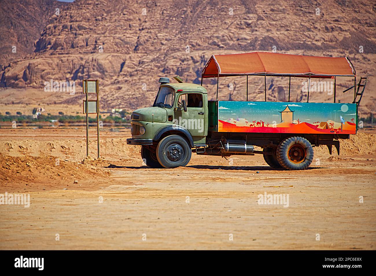 An old and rusty truck in various colors parked in the desert Stock Photo