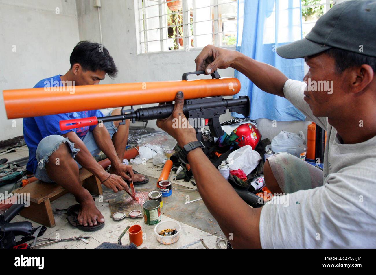 Rolando Santos, tries to fit a big plastic tubing into a plastic toy gun  inside their workshop Wednesday, Dec. 20, 2006 in the town of Kawit in  Cavite province south of Manila.