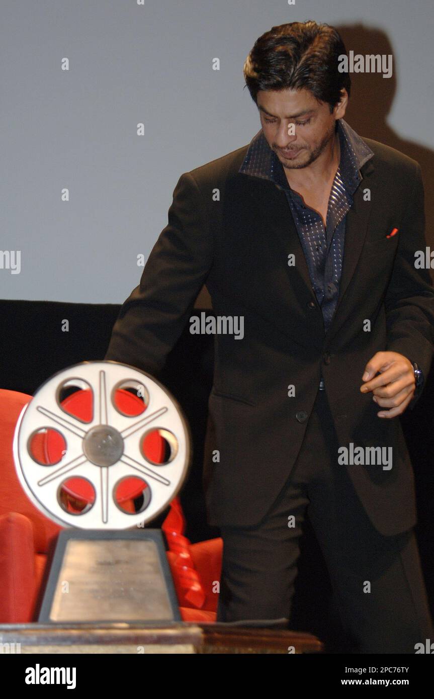 Indian actor Shahrukh Khan, looks at the award he received from Abdul ...