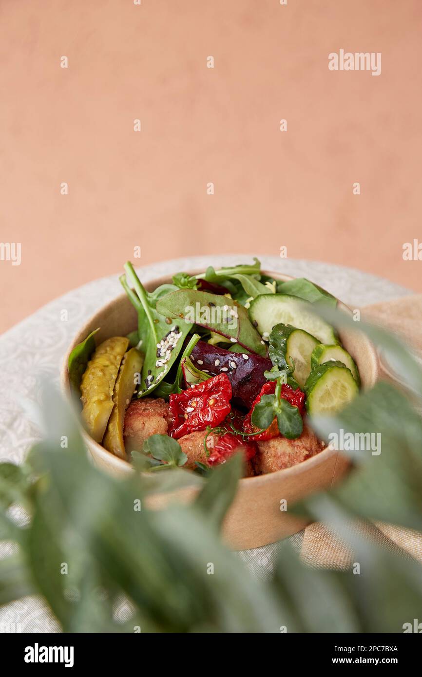 Vegan superfood take away bowl with fresh vegetables, hummus meatballs, pea sprouts and greens with copy space. Plant based diet. Stock Photo