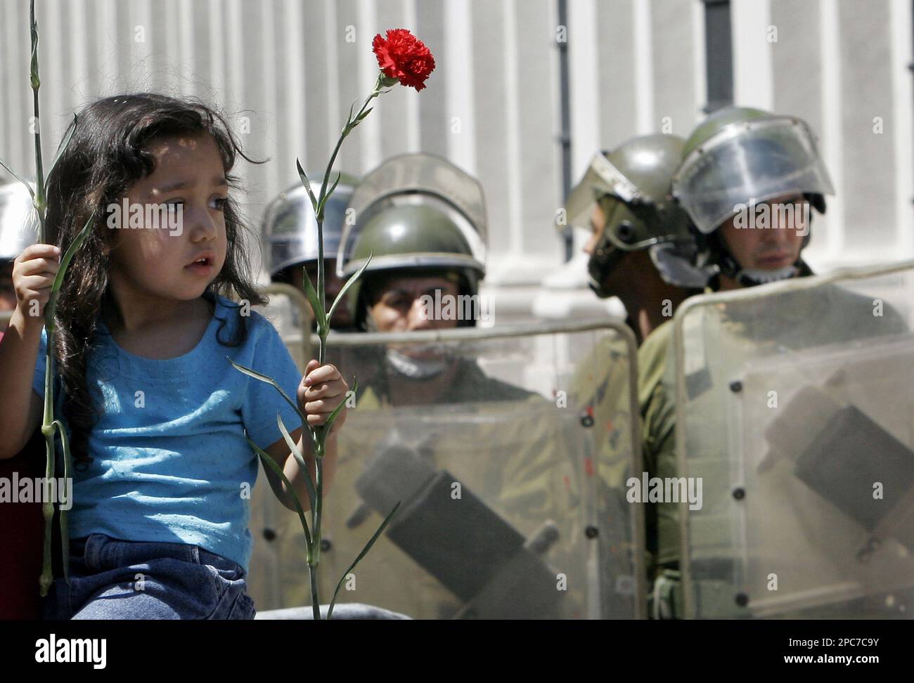 A child holds red carnations next to riot police during celebrations in ...
