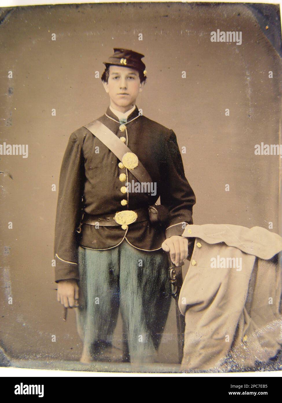 Unidentified young soldier in union uniform next to chair draped with