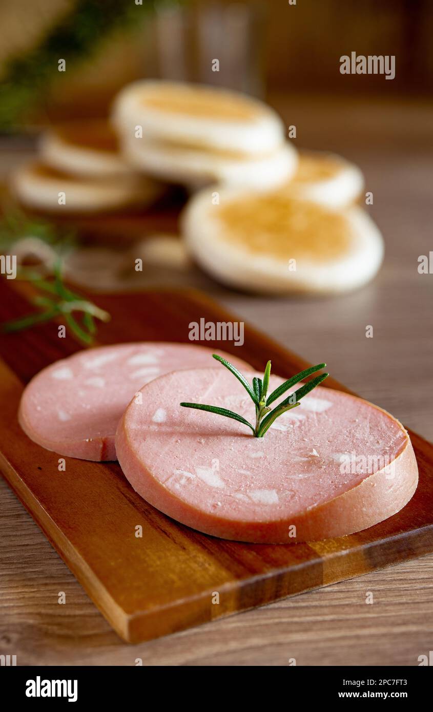 slices of Bologna IGP mortadella on a rustic wooden cutting board and Modenese tigelle Stock Photo