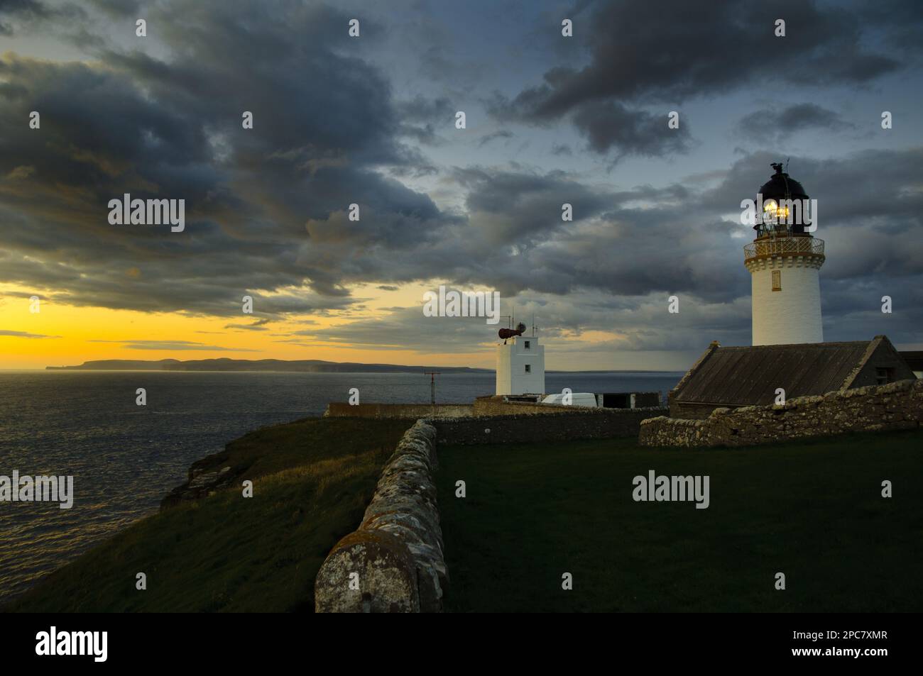 View of clifftop lighthouse at sunset, most northerly point on mainland, with island of Hoy in background, Dunnet Head Lighthouse, Easter Head, Dunnet Stock Photo