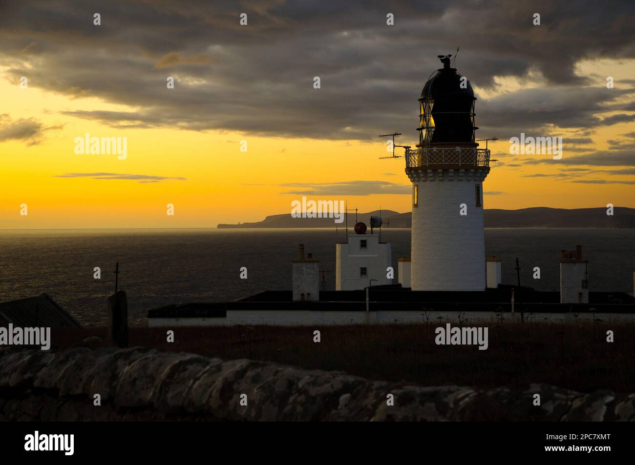 View of clifftop lighthouse at sunset, most northerly point on mainland, with island of Hoy in background, Dunnet Head Lighthouse, Easter Head, Dunnet Stock Photo