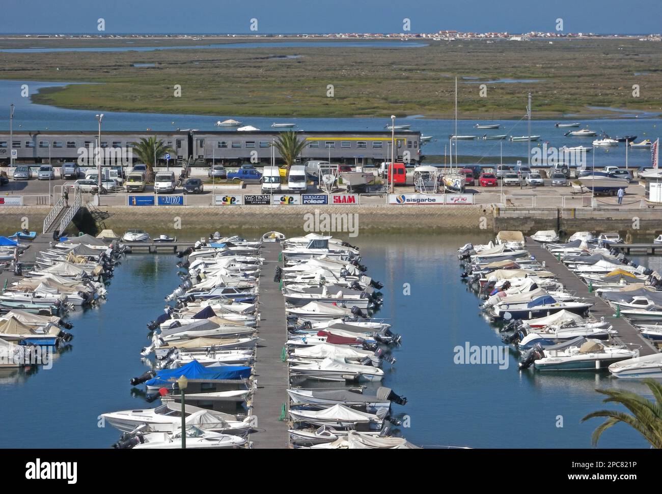 View over marina with passing train, with estuary and salt marsh habitat in the background, Faro, Algarve, Portugal Stock Photo