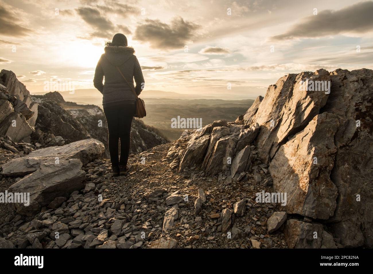 A woman stands with her back on the edge of the cliff. Rocky mountain ...