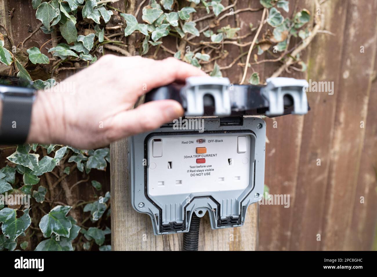 Homeowner showing a fully opened, double gang electrical socket and combined circuit breaker. Note the rubber casket giving a weatherproof seal. Stock Photo