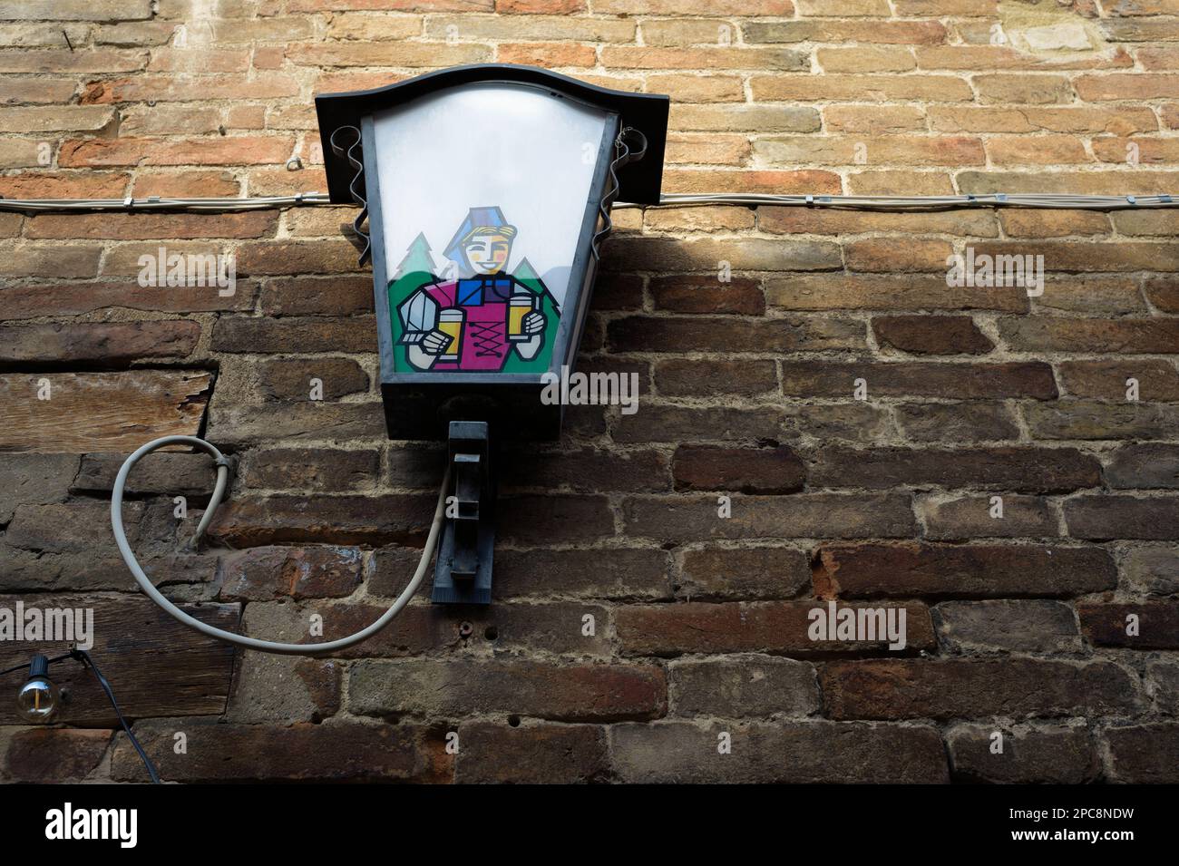 Vintage sreet lamp with a beer brewery sign and the icon of a smiling girl with beer glasses on an old brick wall Stock Photo