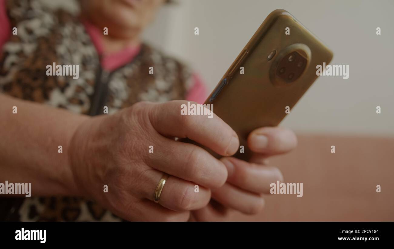 Connected and Engaged: Close-Up of Elderly Woman Hands Messaging on Smartphone Stock Photo