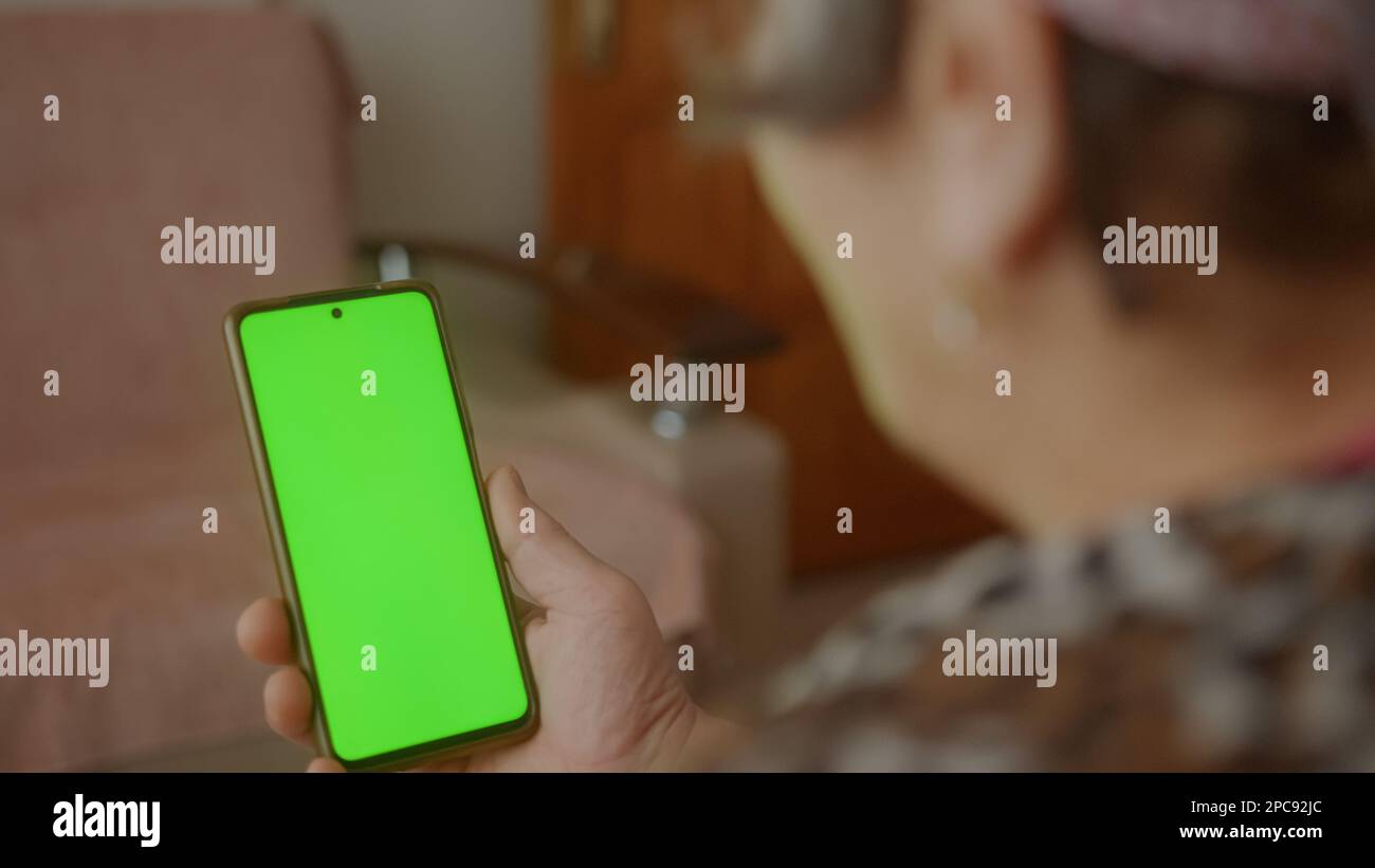 Connected and Tech-Savvy: Senior Woman Using Green-Screen Smartphone for Video Chat or App Stock Photo