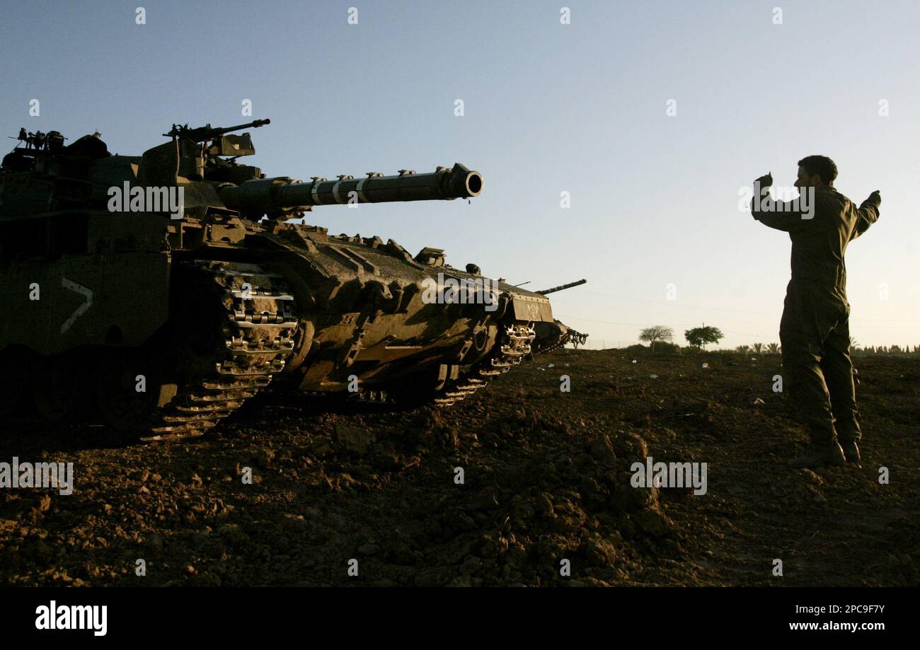 An Israeli soldier directs a tank at a military staging area near Kibbutz Mefalsim in southern Israel, after leaving the Gaza Strip, early Sunday, Nov. 26, 2006. A truce meant to end five months of deadly Israeli-Palestinian clashes went into effect throughout the Gaza Strip early Sunday, bolstering hopes of coaxing moribund peace talks back to life.The Israeli military said all troops were withdrawn from Gaza in the hours before the 6 a.m. cease-fire, announced Saturday, went into force. Streets in northern Gaza were empty immediately after the truce took hold. (AP Photo/Emilio Morenatti) Stock Photo