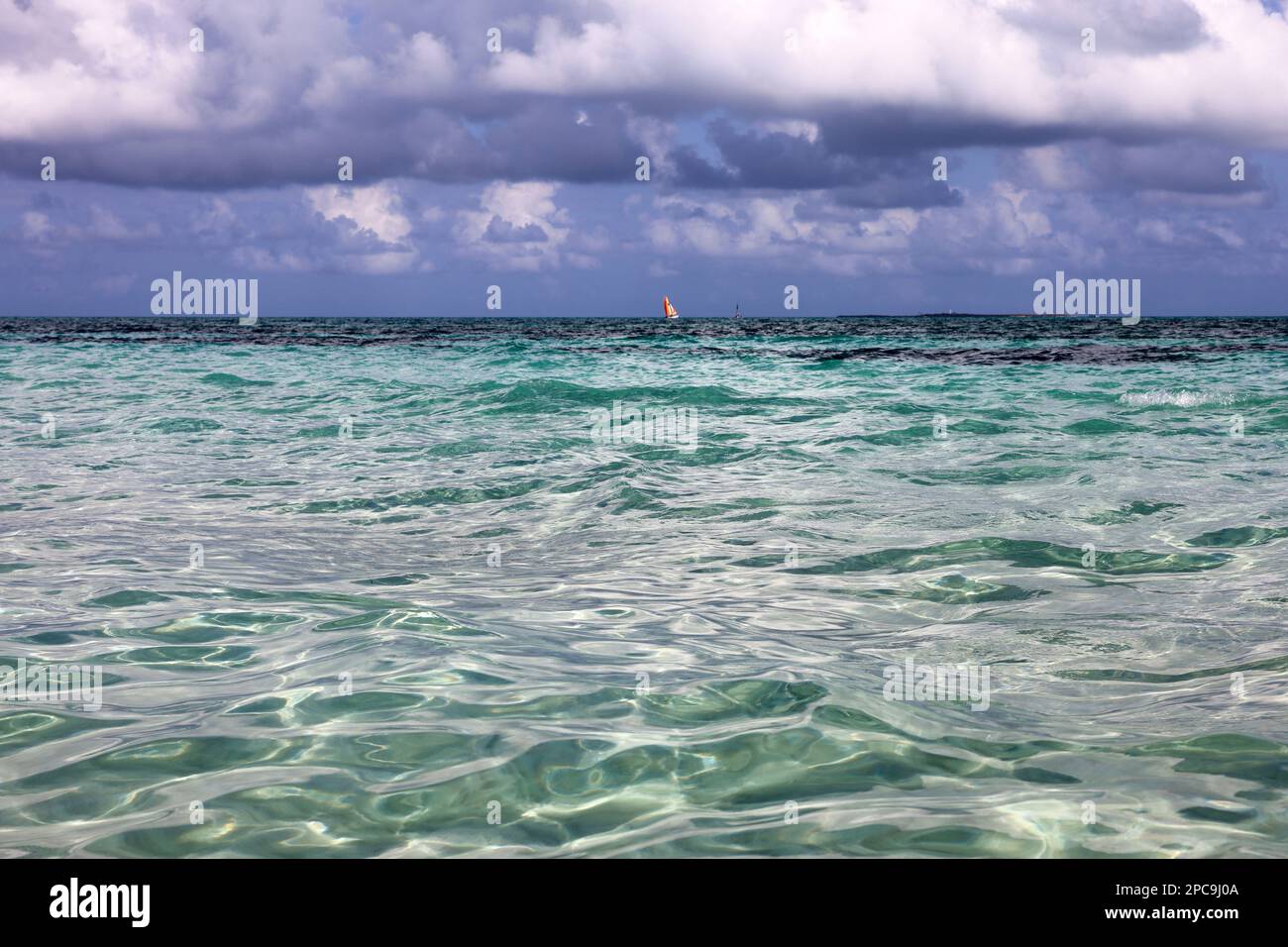 Sea water surface, sailboats on horizon, sky with storm clouds. Tropical beach, background for holidays and vacation Stock Photo