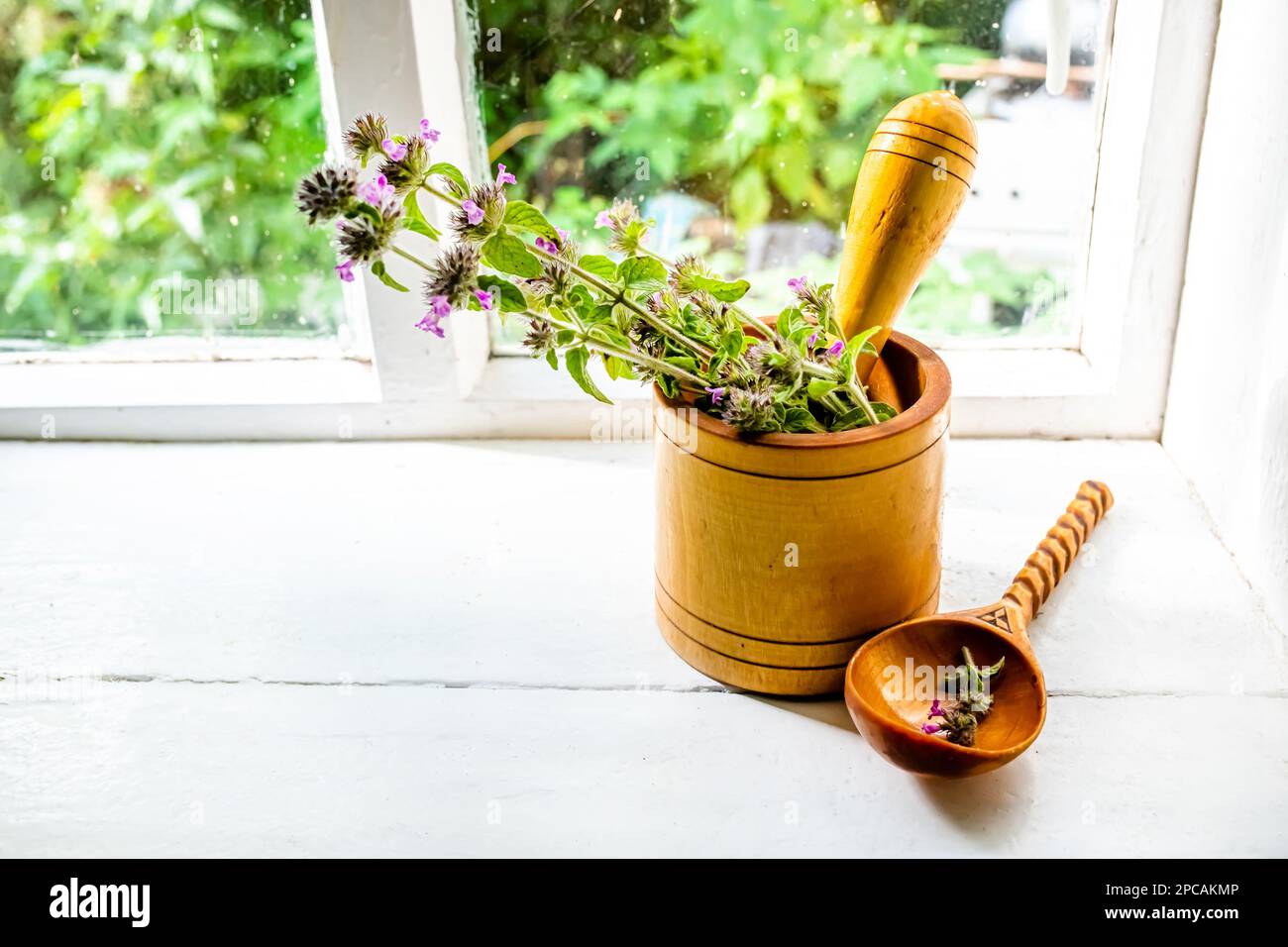 Still life with a bouquet of flowering Gemeiner Wirbeldost, Clinopodium vulgare, wild basil on an old vintage windowsill with wooden frames Stock Photo