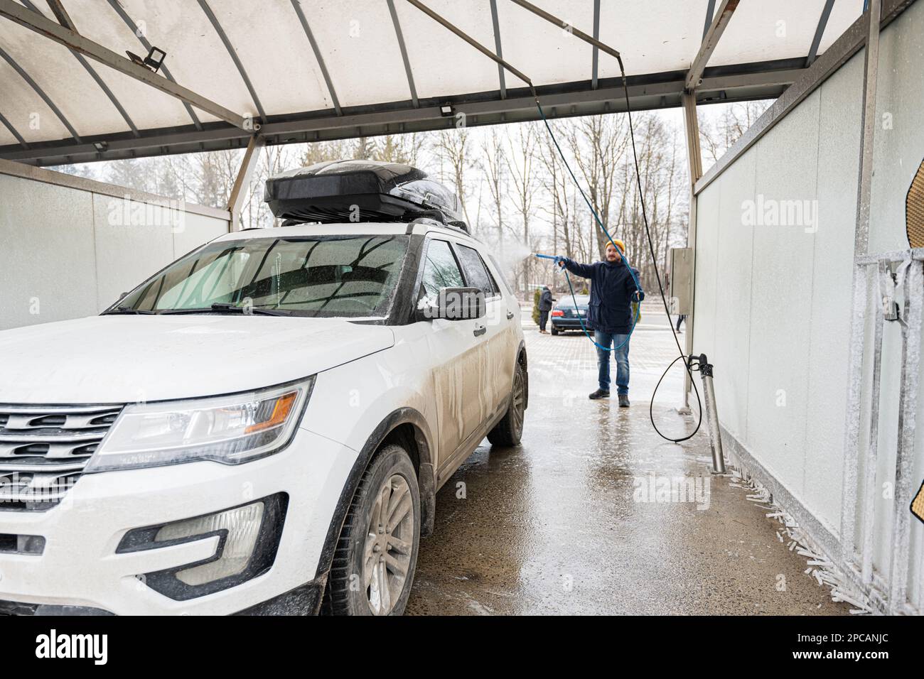 Man washing american SUV car with roof rack at a self service wash in