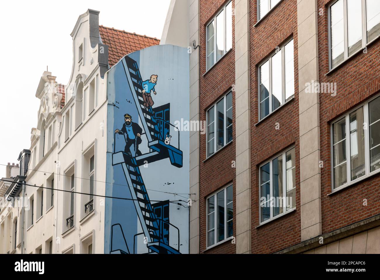 Famous mural of TinTin, captain Haddock and Snowy descending stairs as a wall mural in Brussels opposite the mannequin pis. Stock Photo