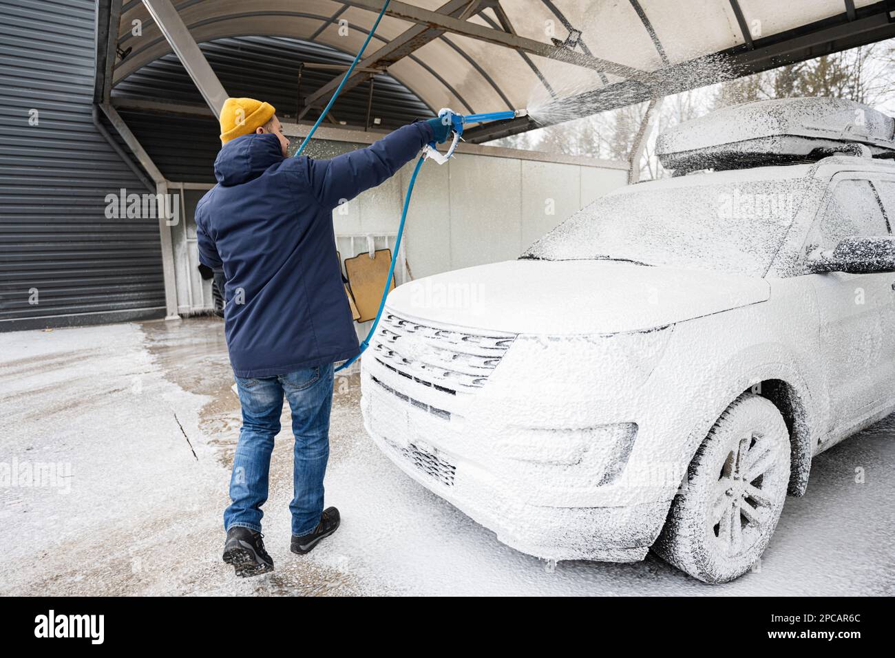 Man washing american SUV car with roof rack at a self service wash in cold weather Stock Photo