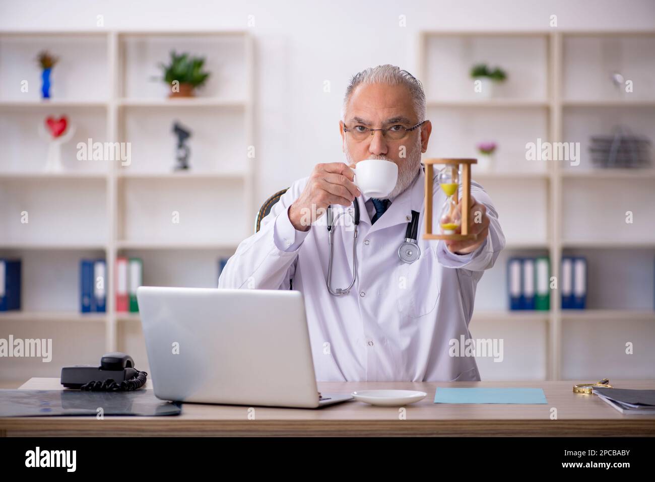 Old doctor in time management concept Stock Photo