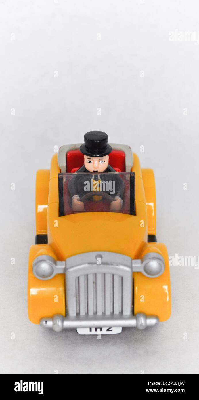 Sir Topham Hatt (The Fat Controller) figure driving a yellow plastic car from the Thomas the Tank Engine series Stock Photo