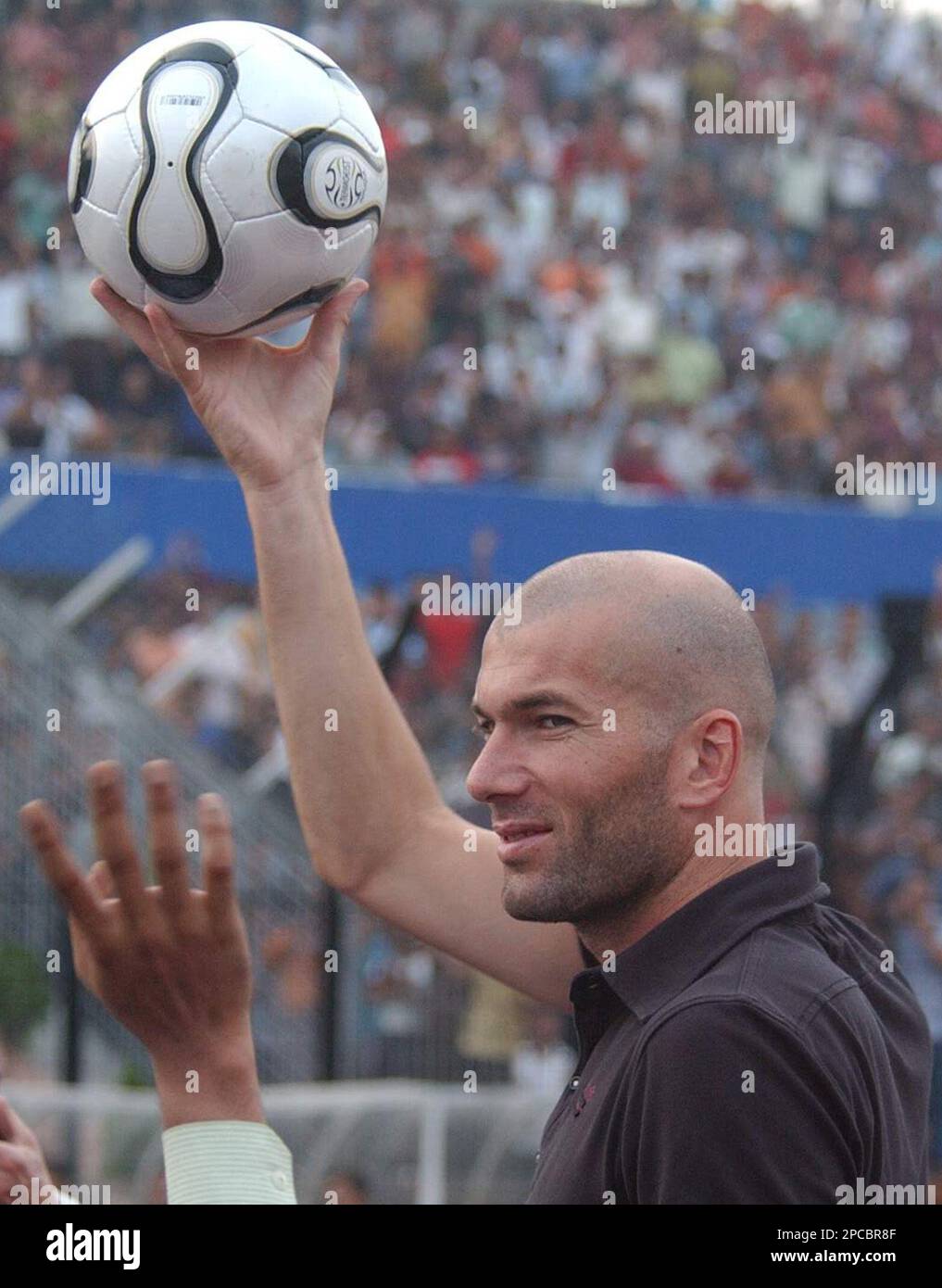 French Footballer Zinedine Zidane holds up a soccer ball to cheering ...
