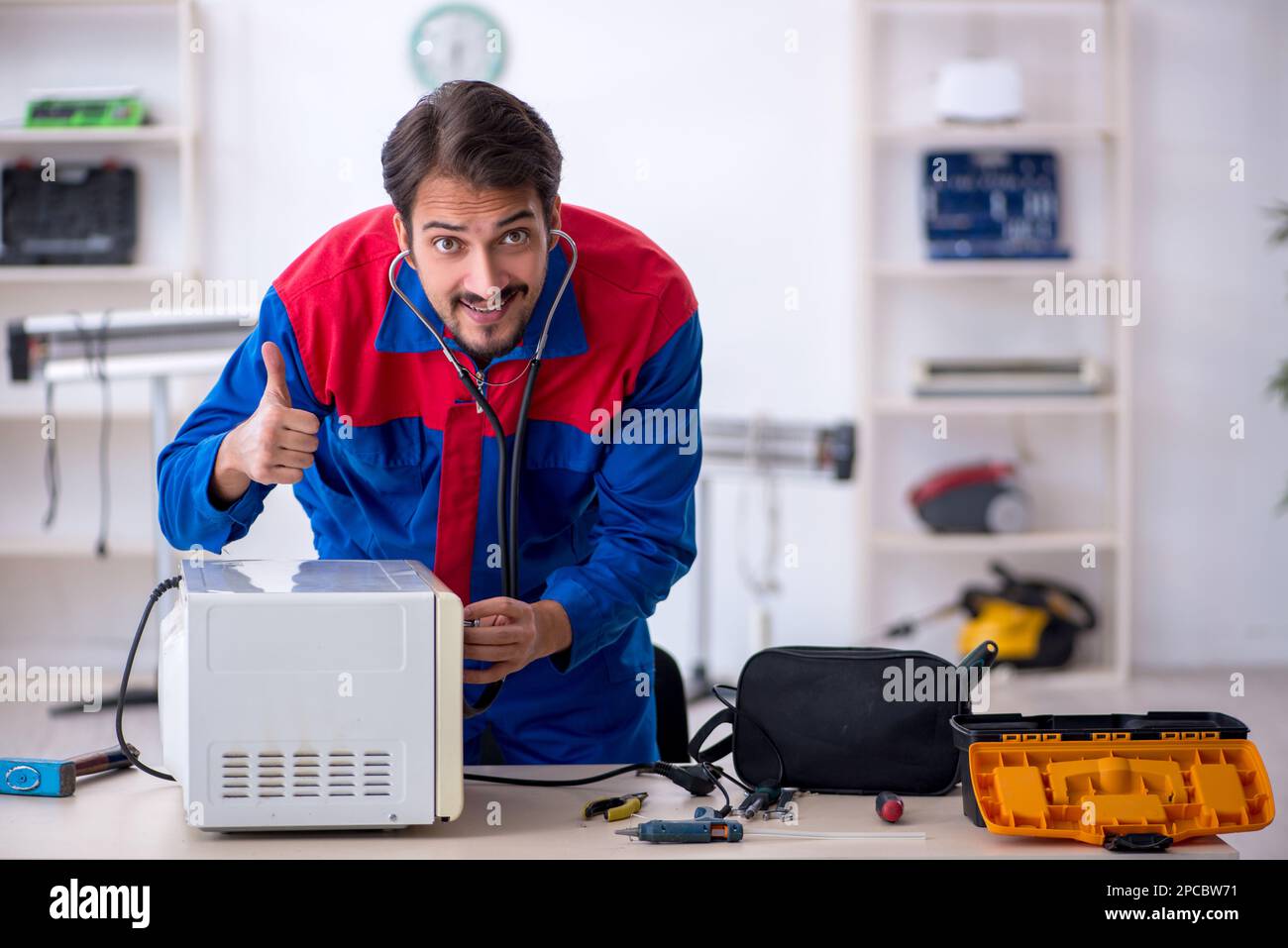 Young repairman repairing oven at workshop Stock Photo