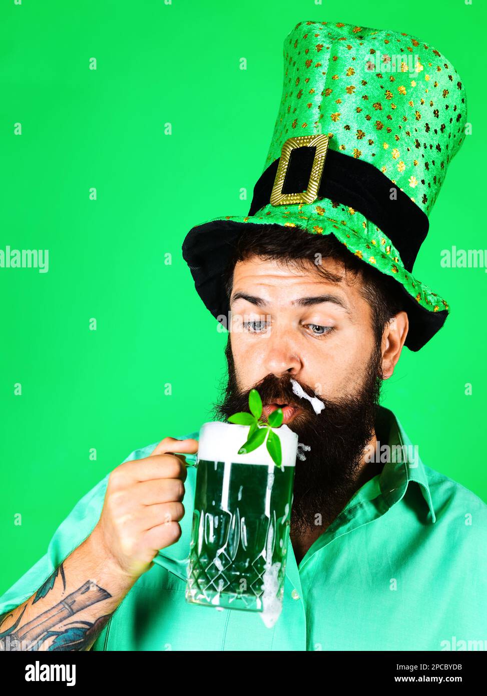 Saint Patricks Day pub party. Bearded man with mug of green beer. Handsome man drinking green beer with shamrock on Patrick day. Bearded male in Stock Photo