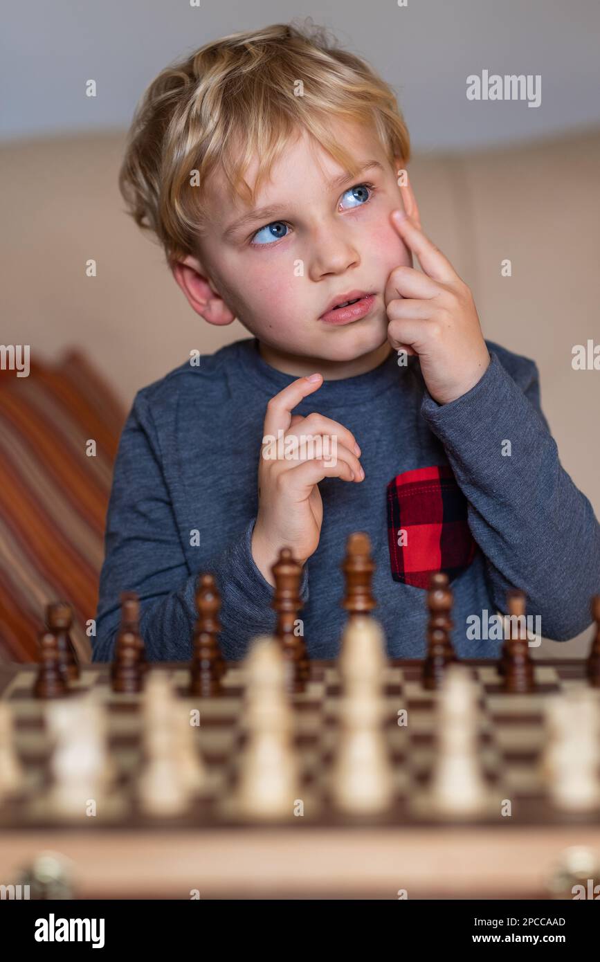 Pupil kid thinking about his next move in a game of chess. Concentrated  little boy sitting at the table and playing chess Stock Photo - Alamy