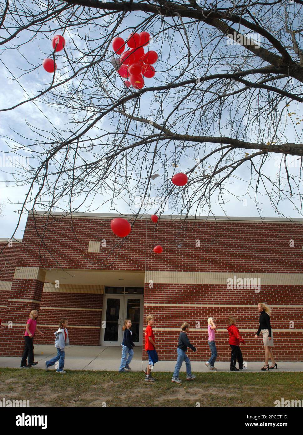 Elementary students and their teacher head back to class past balloons