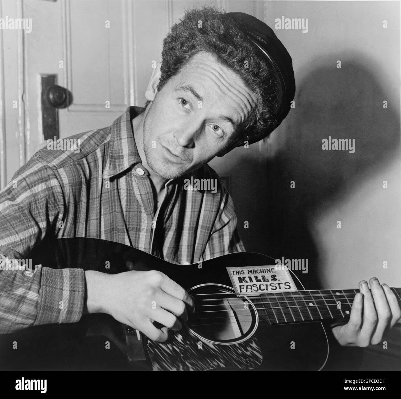 1943 , 8 march , USA :  The celebrated  american Country   singer  WOODY GUTHRIE (born Woodrow Wilson Guthrie , 1912 - 1967 ). Photo by by Al Aumuller . Is best known as an American singer-songwriter and folk musician, whose musical legacy includes hundreds of political, traditional and children's songs, ballads and improvised works. He frequently performed with the slogan 'This Machine Kills Fascists' displayed on his guitar.  His best known song is probably ' This Land Is Your Land '- CHITARRA - chitarrista - guitarist - MUSIC - ROCK - MUSICA LEGGERA - portrait - ritratto  - musicista - musi Stock Photo