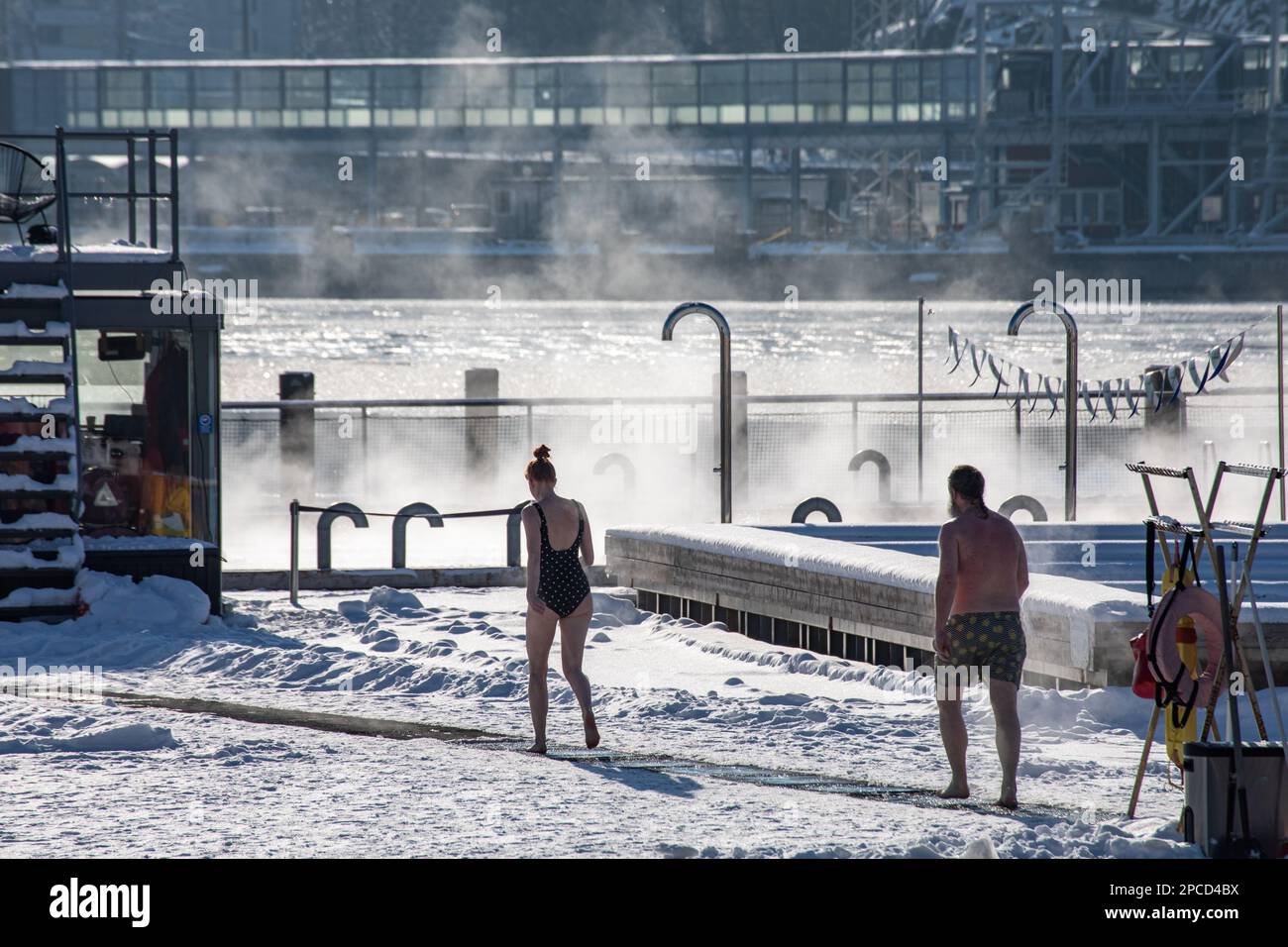 People going to swimming pool after sauna at Allas Sea Pool floating pool deck on a sunny winter day in Helsinki, Finland Stock Photo