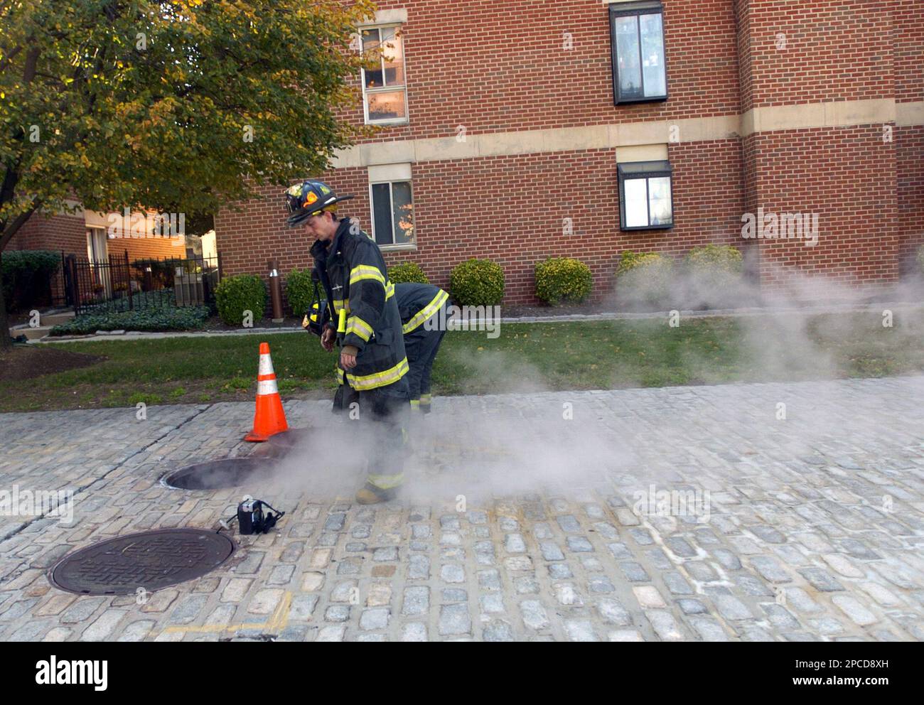 A Baltimore city firefighter takes measurements of gas in a manhole in ...