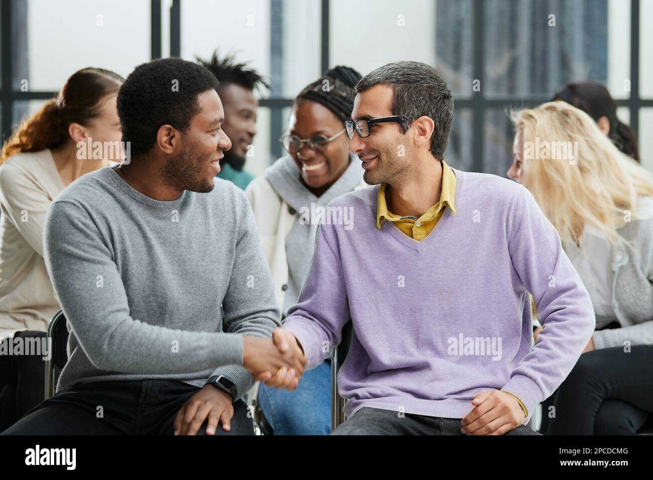Happy multiethnic employees having fun while discussing project, sharing ideas, informal brainstorming sitting on chairs Stock Photo