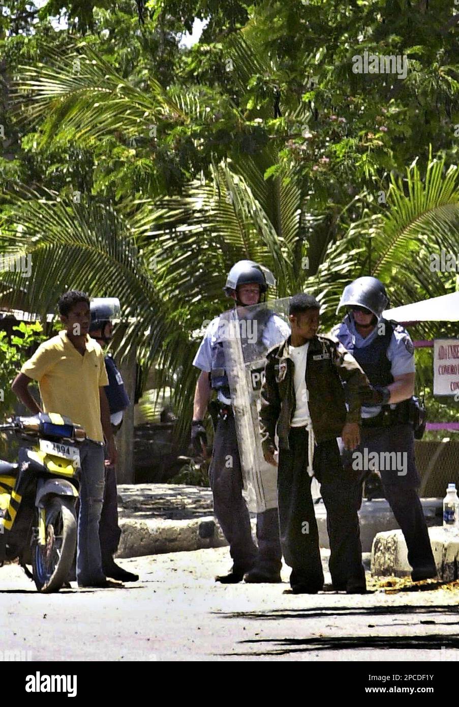Australian police officers in riot gears frisk an East Timorese man in ...