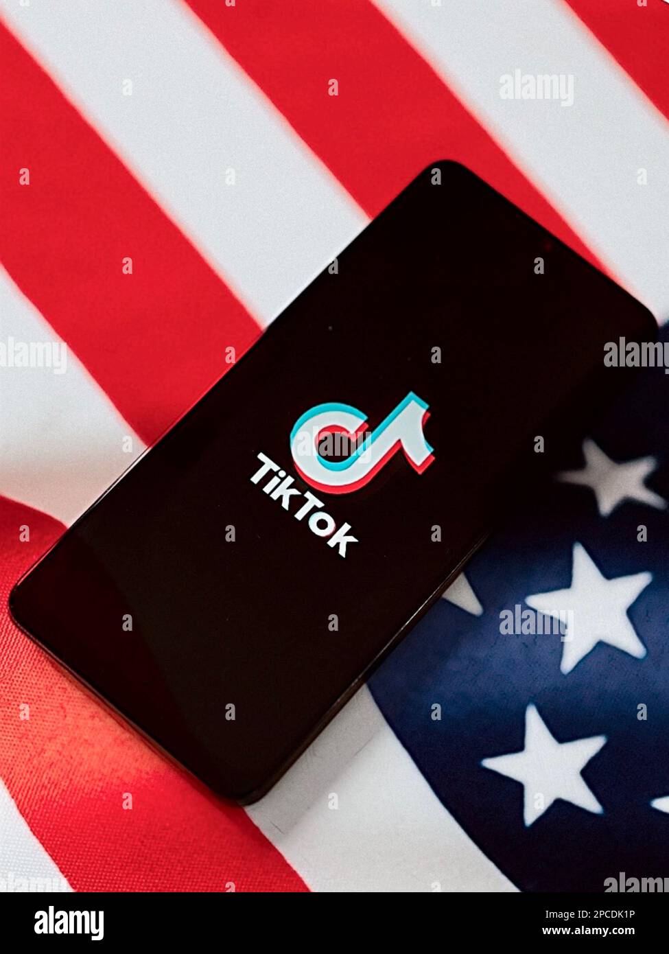 Mobile phone device showing TikTok logo on screen with the American USA flag in the background Stock Photo