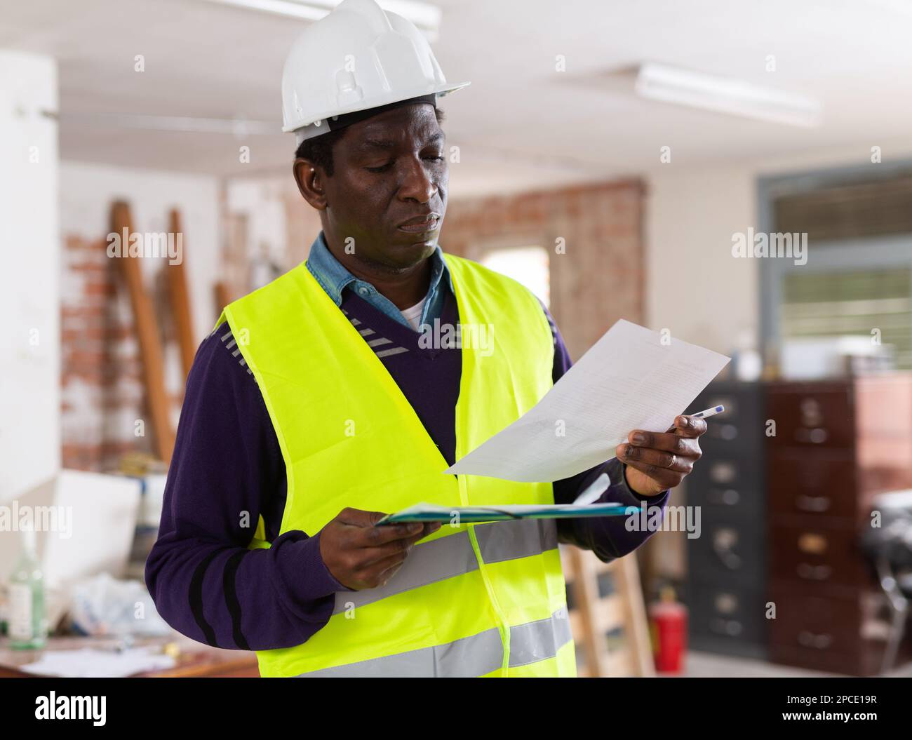 Man construction worker with document inside apartment Stock Photo