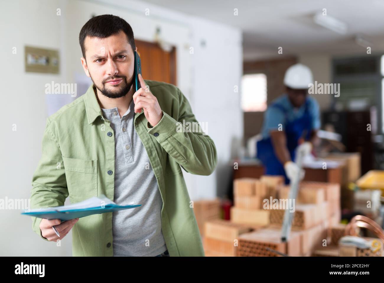 Construction manager with paper folder having telephone conversation Stock Photo
