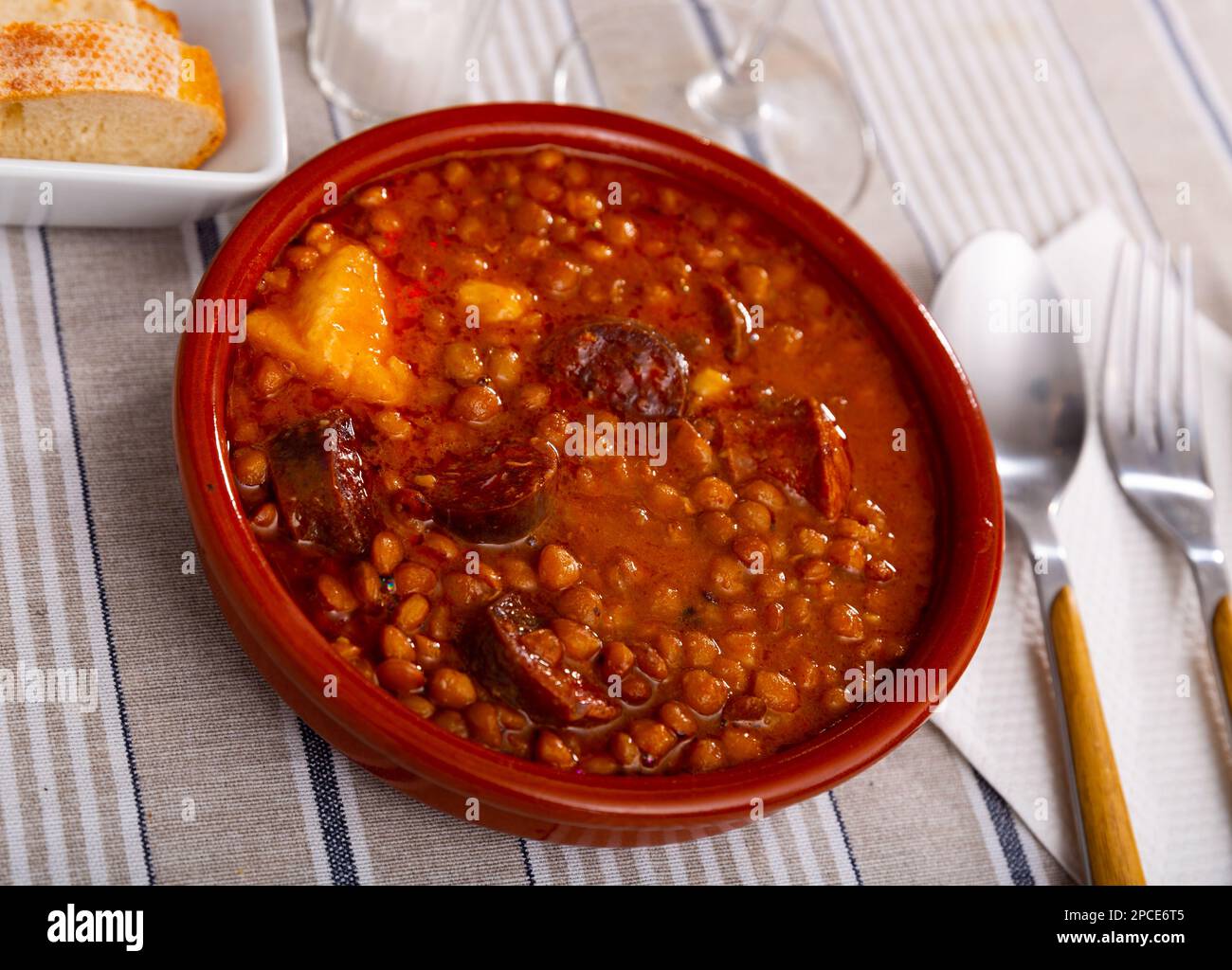 Stew of lentils with meat, chorizo and vegetables in clay bowl Stock Photo