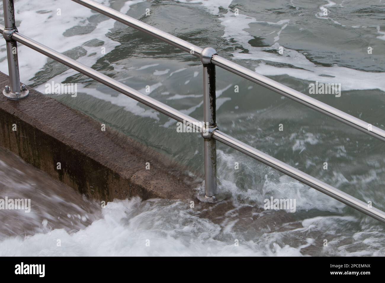 Waves crashing over steps and railings at high tide. Bristol Channel
