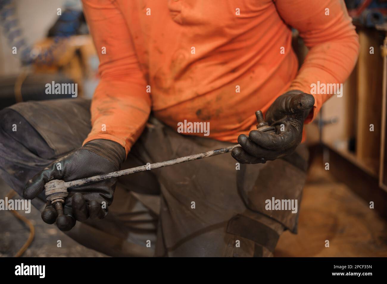 Mechanic man repairs the undercarriage of the car. A man repairs a car in a garage. Car wheel repair Stock Photo