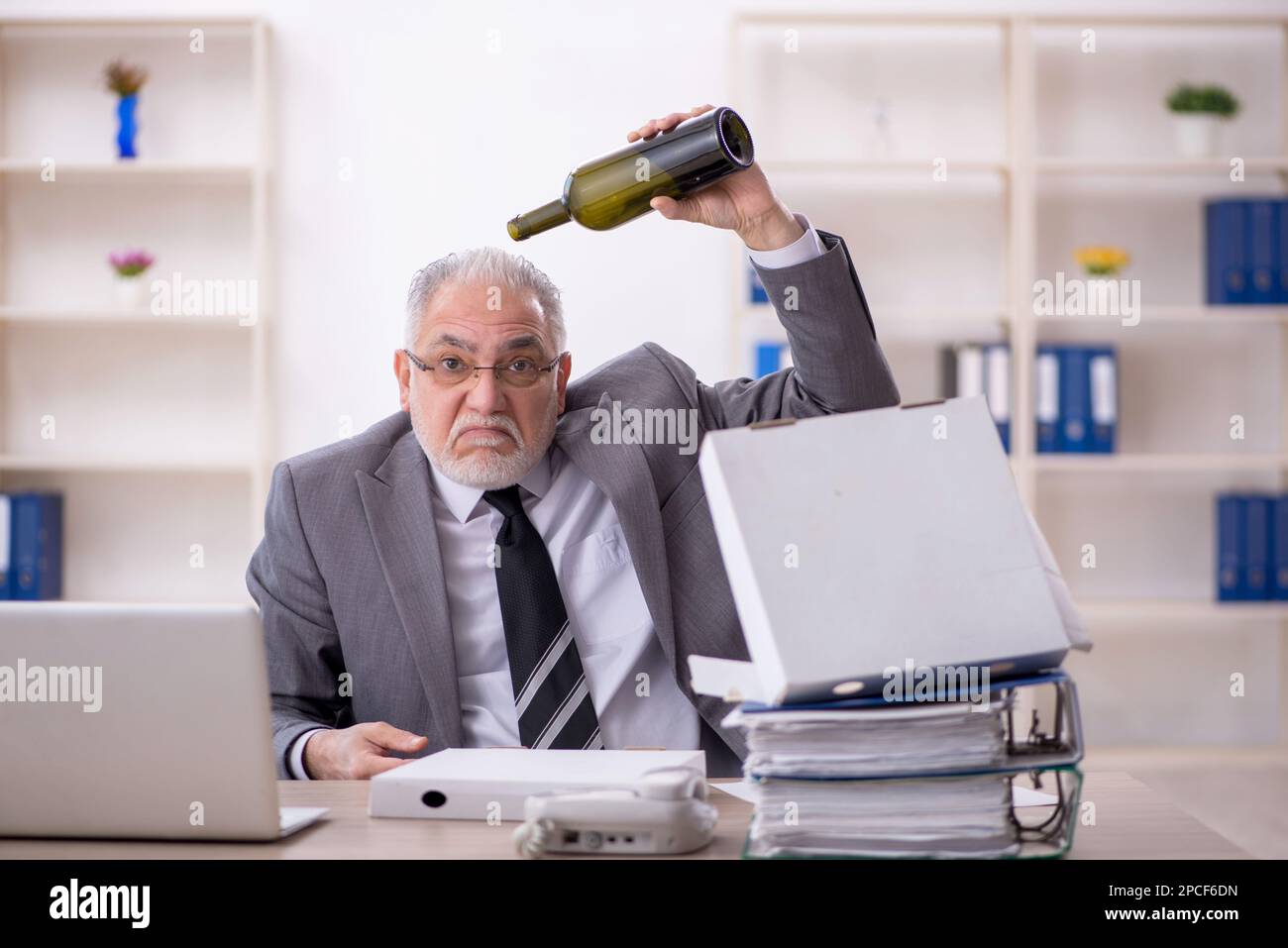 Old employee drinking alcohol at workplace Stock Photo - Alamy