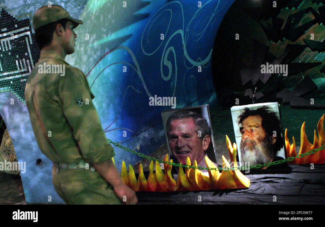 An Iranian revolutionary guards soldier looks to photos of US President George W. Bush, left, and former Iraqi President Saddam Hussein, in a exhibition marking the 26th anniversary of the outset of the Iran - Iraq war (1980-1988) in Tehran, Iran , Sunday, Sept. 24, 2006. (AP Photo/Hasan Sarbakhshian) Stock Photo