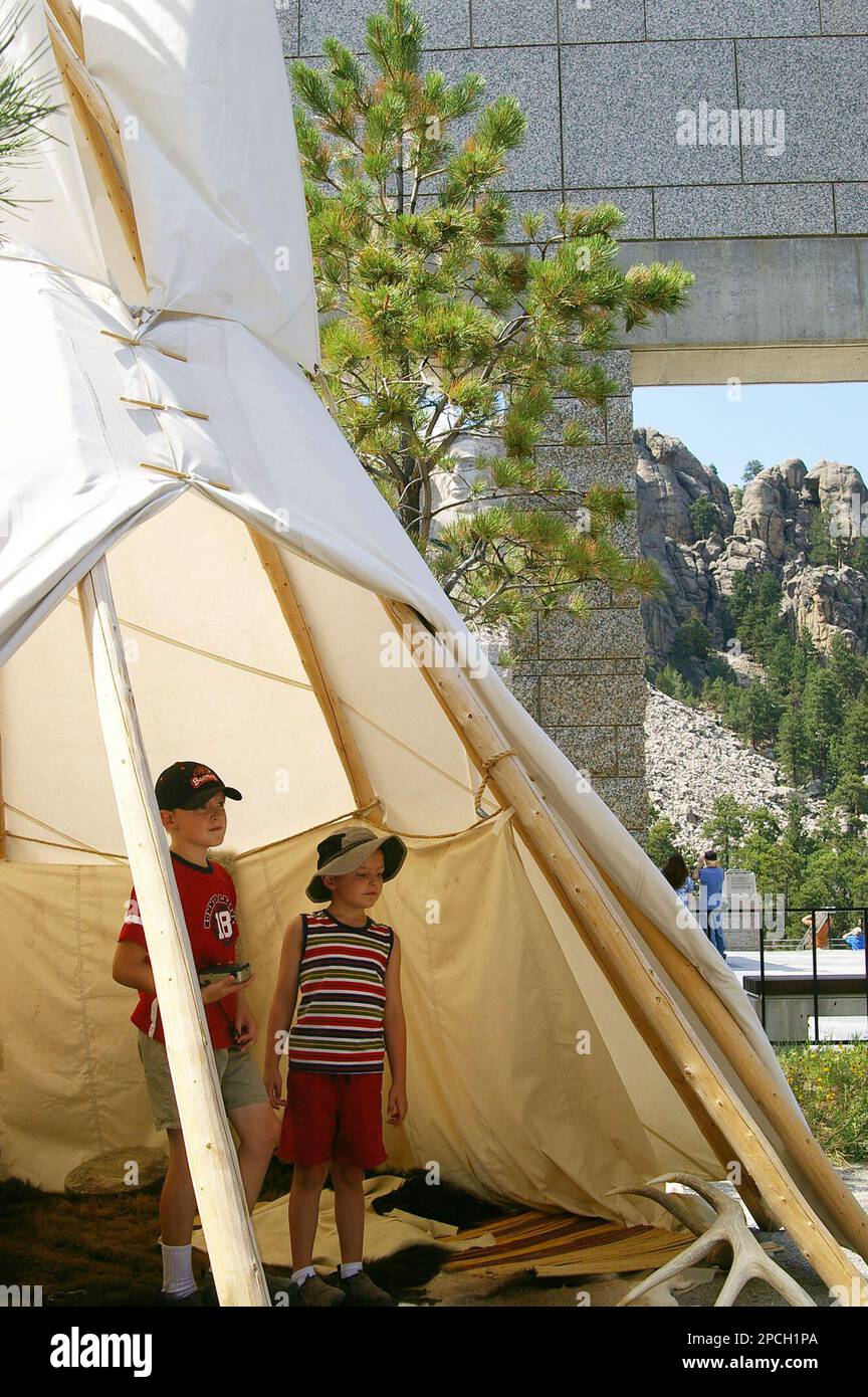The carved head of Abraham Lincoln is seen in the background as 6-year-old  Thomas Evans, right, and his 9-year-old brother, Peter, look through a tipi  set up at Mount Rushmore National Memorial,