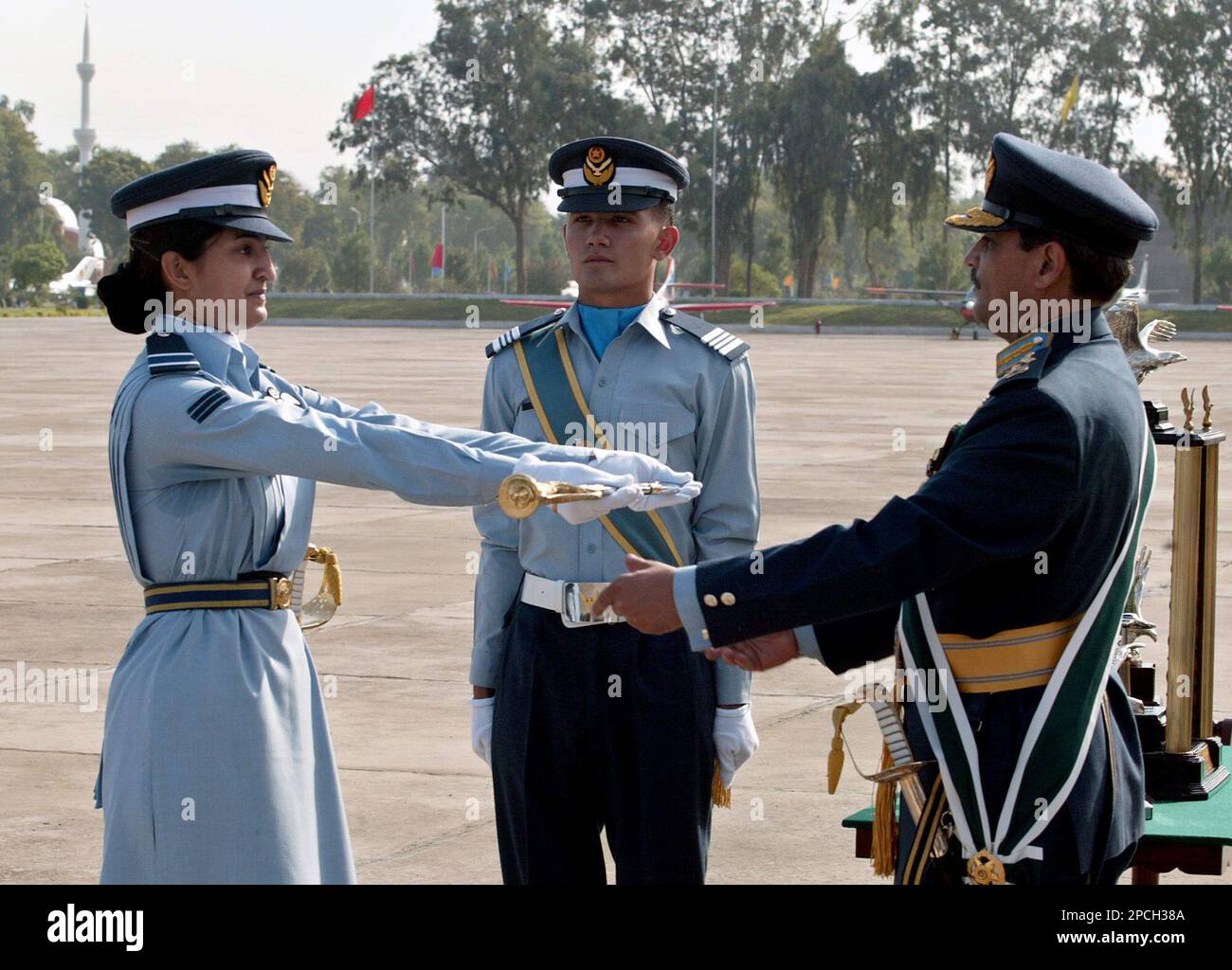 Pakistan Air Force Chief, Air Marshal Tanvir Mahmood Ahmed, right, awards sword of honor for best all round performance to an woman flying officer Sahira Amin, left, during a pass-out parade at