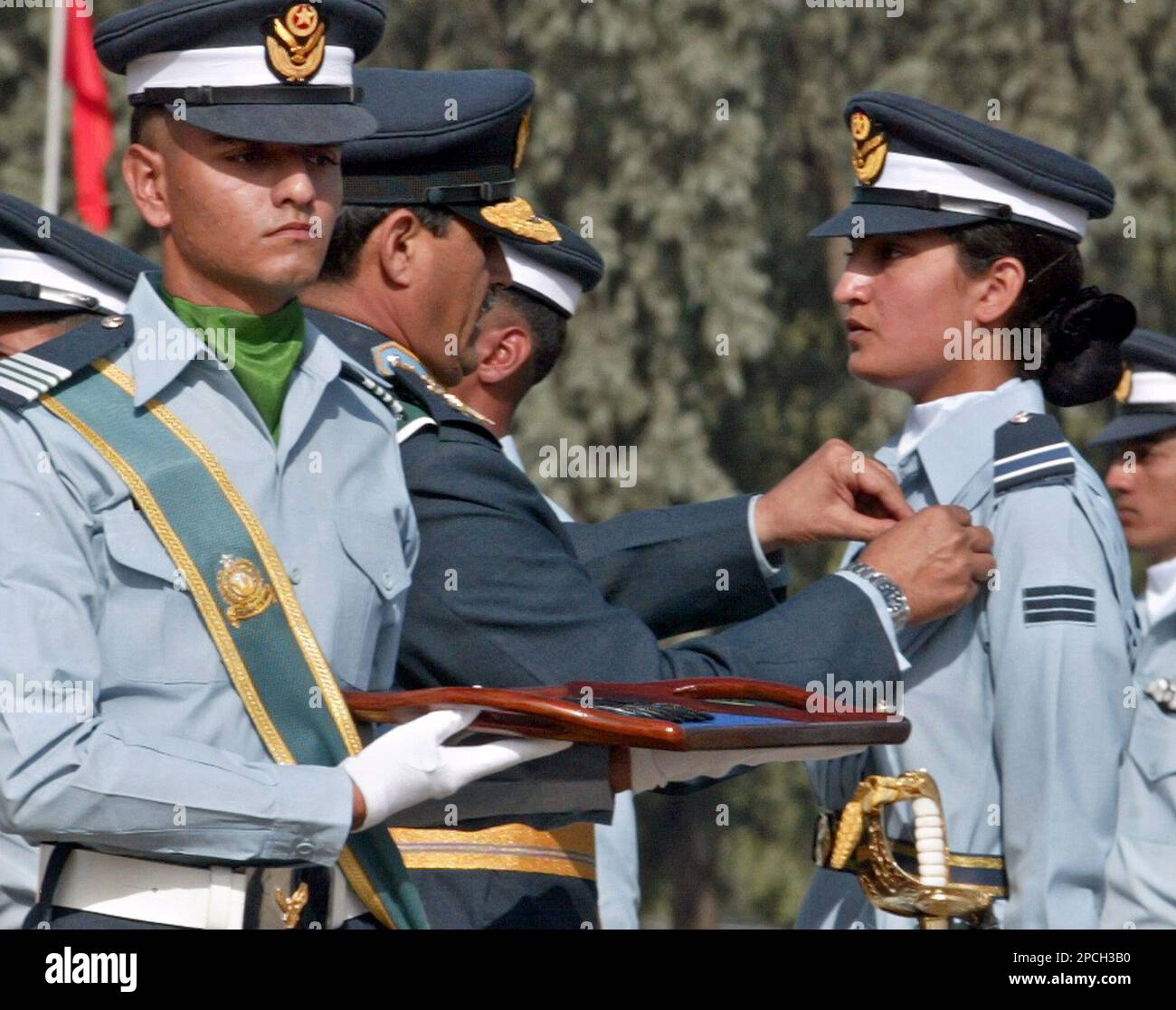 Pakistan Air Force Chief, Air Marshal Tanvir Mahmood Ahmed, center, decorates the flying-badges to an woman flying officer Sahira Amin, right, during a pass-out parade at Pakistan Air Force Base in Risalpur