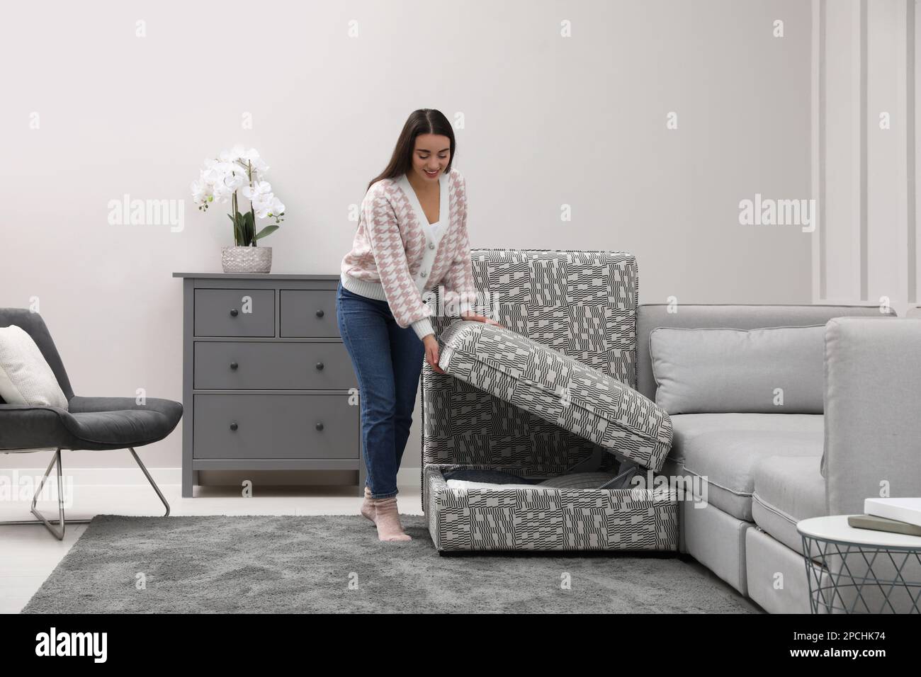 Woman closing modular sofa section with storage in living room Stock
