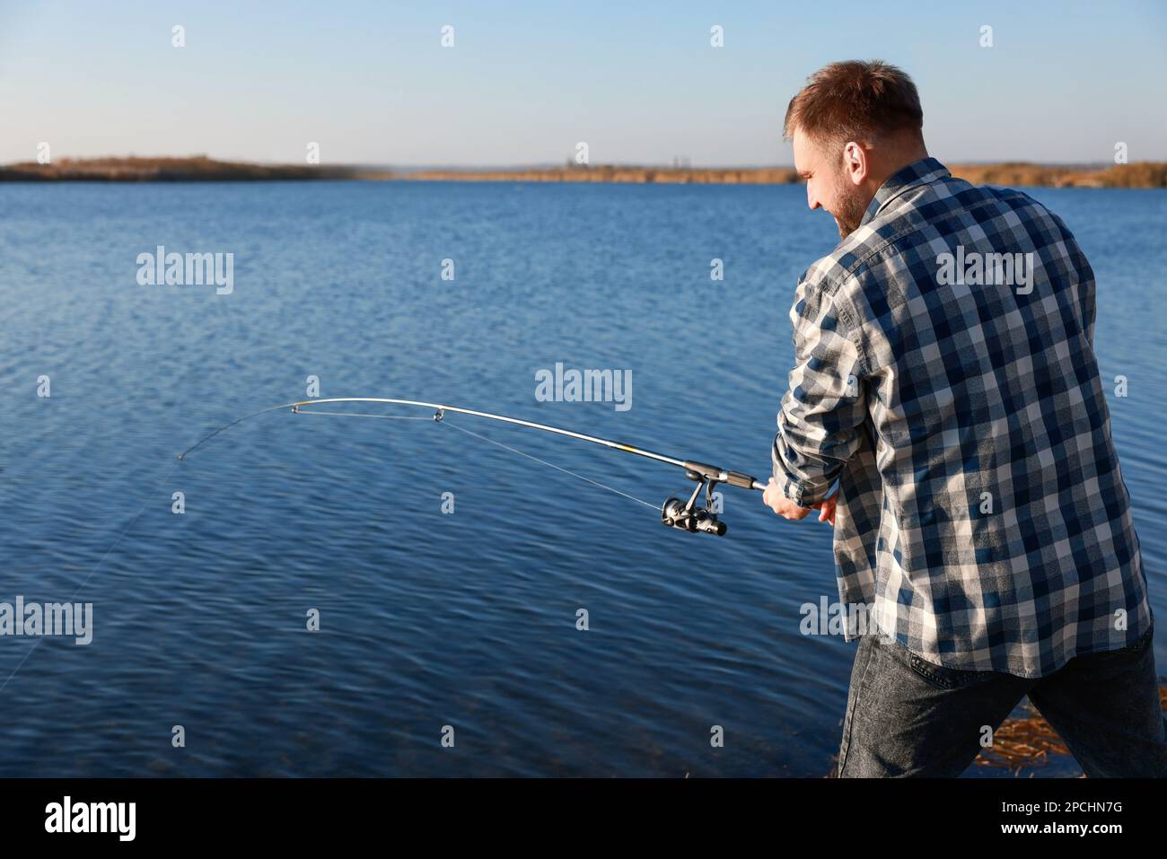 Fisherman with rod fishing at riverside. Recreational activity