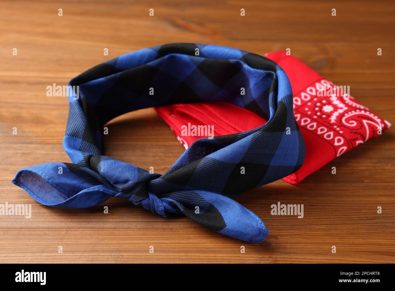 Tied and folded bandanas with different patterns on wooden table Stock Photo